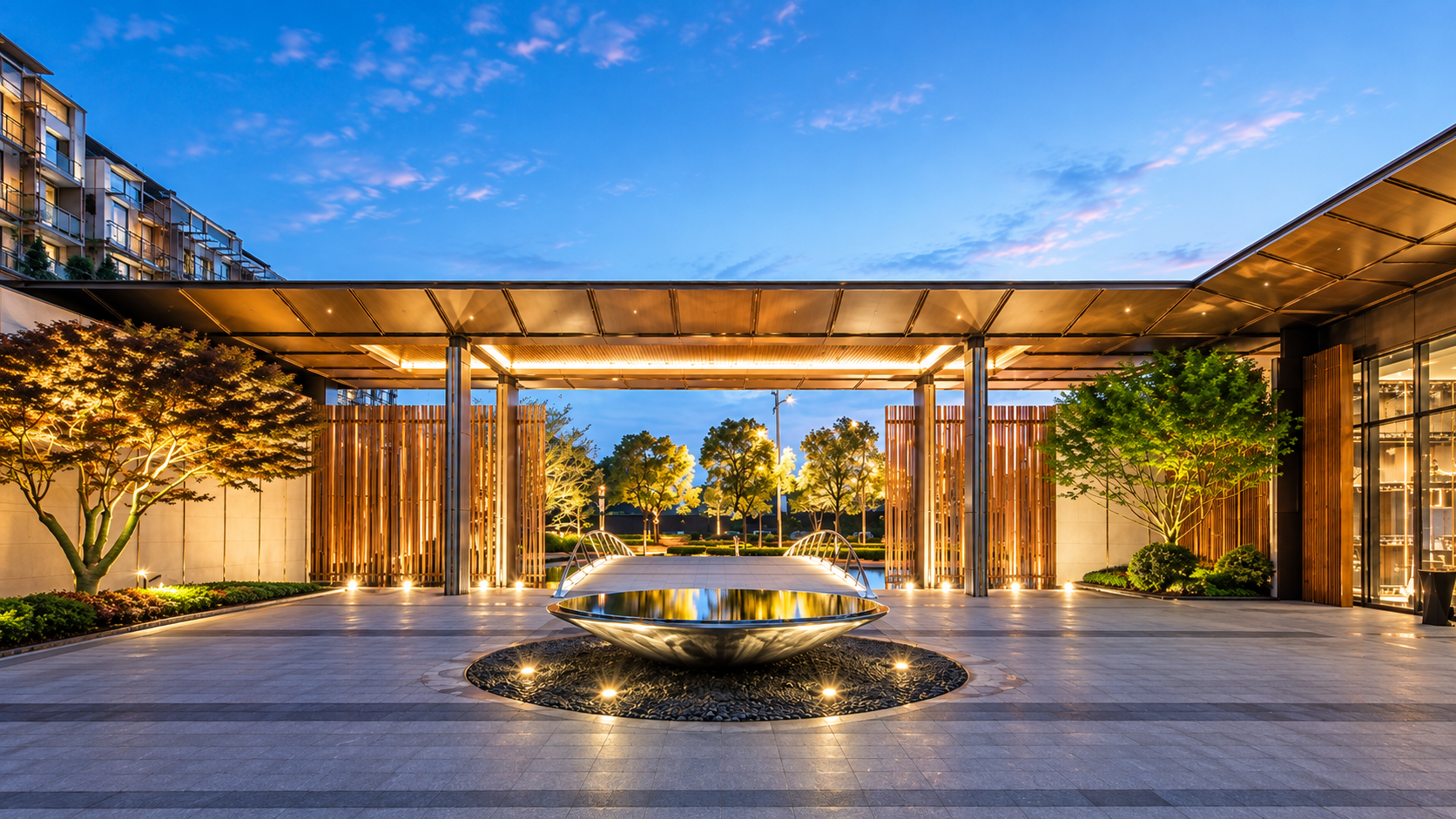 Arrival courtyard at dusk with a sculptural water feature and timber screens